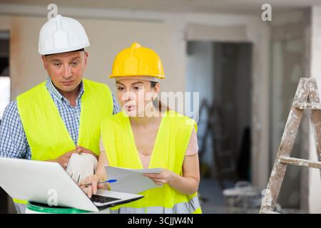 Woman architect and man engineer using laptop in construction site Stock Photo