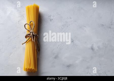 Uncooked Spaghetti Pasta with Natural Rope on Gray Background Top View Copy Space Stock Photo