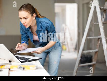 Woman with laptop at house being renovated Stock Photo