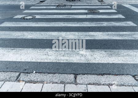 Pedestrian zebra crossing white stripes over asphalt black gray traffic road outdoor Stock Photo