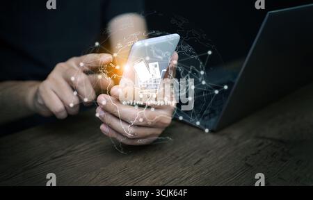 Digital online shopping with mobile phone and holographic shopping cart icon, representing global e-commerce growth, internet retail, and cross-border Stock Photo