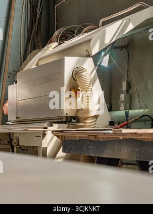 Industrial edge banding machine for applying laminate or edge tape to wooden panels in furniture production Stock Photo