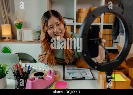 the business owner or an entrepreneur is doing live marketing to sell her products that is clothing through online channels for all customers who like Stock Photo
