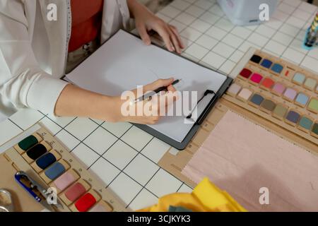 An Asian designer is sketching her idea of her new clothes collection to be stylish by using her creativity, a talented designer works on design a fas Stock Photo