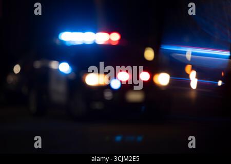 Abstracted view of police lights on a city street at night with lens flare. Stock Photo