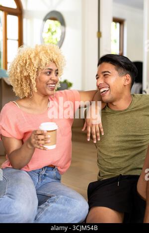Young couple laughing together at home, enjoying coffee and conversation Stock Photo
