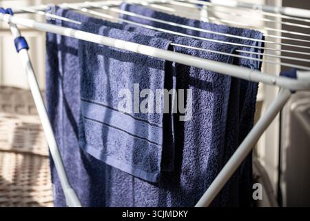 Neatly organized blue towels hang on a drying rack, highlighting their soft texture and fresh appearance, contributing to a cozy and practical home en Stock Photo