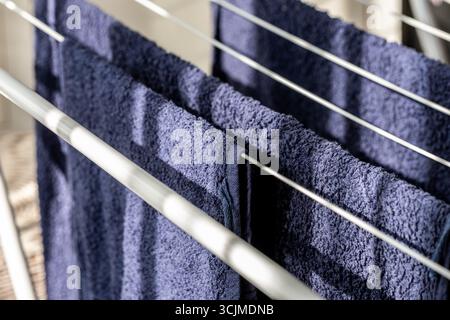 Neatly organized blue towels hang on a drying rack, highlighting their soft texture and fresh appearance, contributing to a cozy and practical ambianc Stock Photo