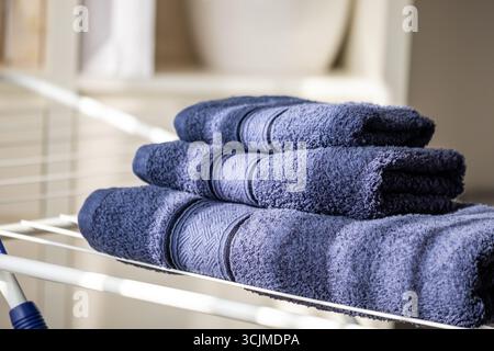Soft navy towels are neatly arranged on a drying rack, emphasizing their organized and fresh appearance, contributing to a cozy and practical environm Stock Photo