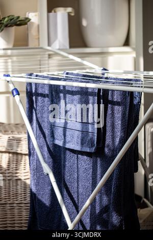Neatly organized blue towels hang on a drying rack, highlighting their soft texture and fresh appearance in a cozy, well-lit environment that enhances Stock Photo