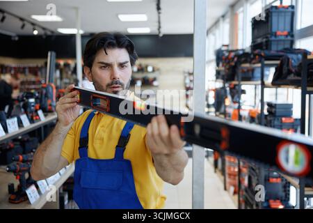 A man worker taking measurements using a bubble level tool inside a store Stock Photo