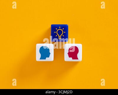 Sharing innovative ideas, teamwork and brainstorming for new business strategies with a light bulb and human heads on colorful blocks Stock Photo