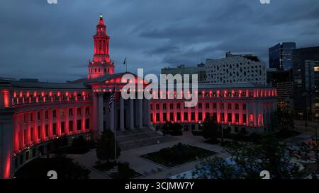 Aerial view of the Denver City and County Building illuminated in a vibrant red glow against the twilight sky, Denver, Colorado, United States. Stock Photo