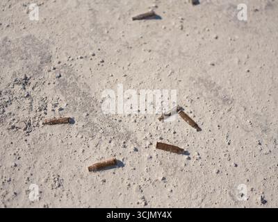 Rusty spent bullet casings scattered on the white chalk quarry ground. War in Ukraine. Symbolic image of the silent traces of war.Top view. Stock Photo
