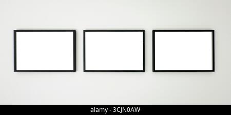 Three horizontal black picture frames hanging on a white wall, clean mockup for artwork, photography, posters, or graphic design presentation in a mod Stock Photo