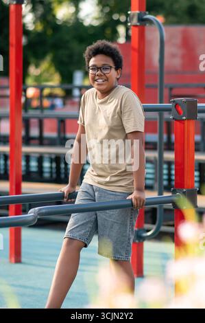 Curly-haired boy in eyeglasses spending time at the playground Stock Photo