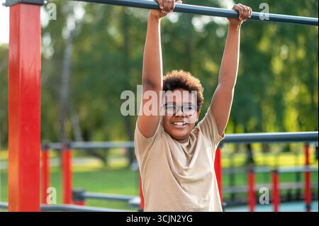Curly-haired boy in eyeglasses spending time at the playground Stock Photo
