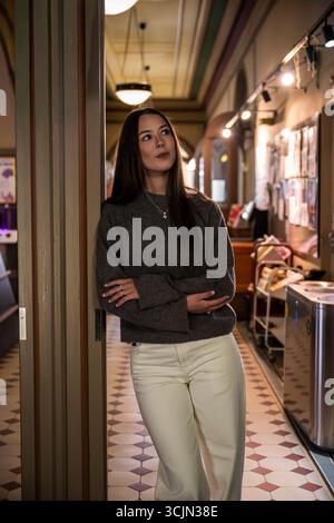 Young woman in grey sweater and pants standing in vintage hallway Stock Photo