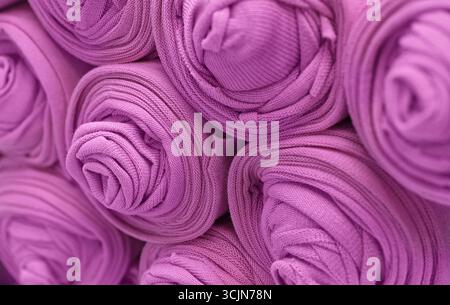 Knitted pink fabric rolled into rolls, close up shot, abstract textile background Stock Photo