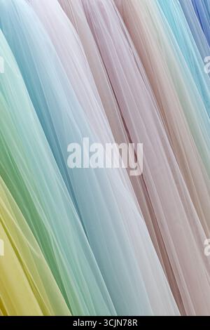 Vertical folds of translucent fabric in various pastel colors, close up shot, abstract textile background Stock Photo