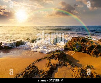 beach with sand at sunset. summer vacation at the seaside. beautiful seascape with calm waves in evening light. landscape at the sea under rainbow and Stock Photo