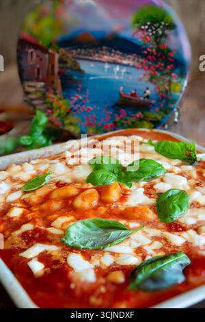 Gnocchi alla sorrentina baking in a pan, featuring fresh basil, cherry tomatoes, and rich tomato sauce, embodying traditional neapolitan cuisine Stock Photo