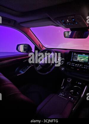 Toyota Highlander interior in the dark. Driver's cockpit filled with purple light, map is shown on infotainment system's screen. Stock Photo