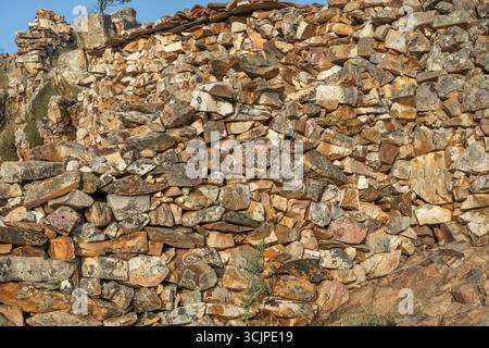 Irregular stone wall in ochre and gray tones, with pronounced joints that highlight the wild and organic texture of the natural rock Stock Photo
