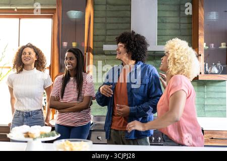 Young friends laughing and chatting together in modern kitchen, enjoying time Stock Photo