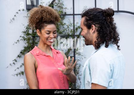 Happy couple celebrating engagement outdoors, woman showing ring with excitement Stock Photo