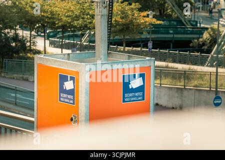 Security Notice Video Surveillance Urban Area Monitoring. Warning signs indicating active CCTV surveillance on a bright orange panel in a modern urban Stock Photo