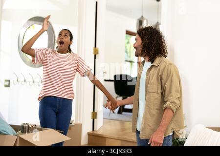 Young diverse couple unpacking moving boxes, feeling excited and joyful in new home Stock Photo