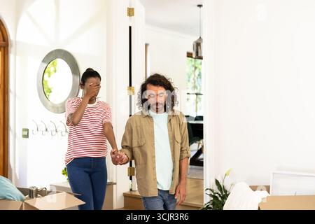 Young diverse couple holding hands, exploring new home, feeling excited and emotional Stock Photo