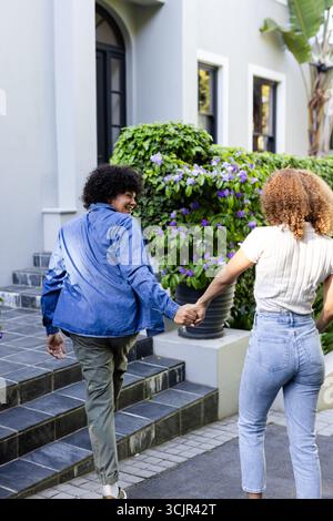 Young diverse couple holding hands walking outside, enjoying sunny day together Stock Photo