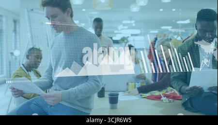 Collaborating six colleagues analyzing digital charts around office table, with laptops and reports Stock Photo