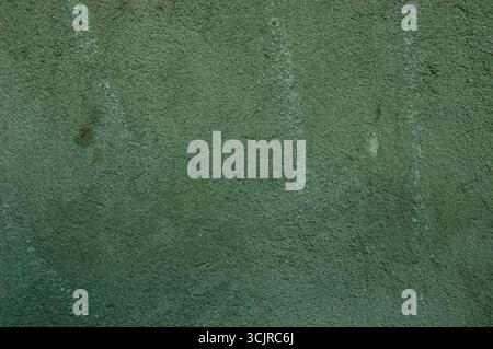 A gray-green concrete wall with stains and scratches, creating a grunge textured background. Stock Photo