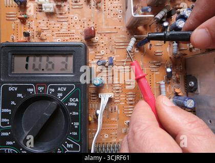 Testing an electronic component with the multimeter. An electrical resistor is testing by a technical staff on circuit board. Stock Photo