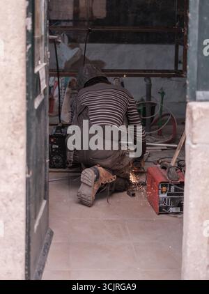 Worker Welding Metal With Protective Gear And Sparks Flying In Workshop Stock Photo