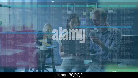 Studying code on digital screen at office, IT professionals wearing gray sweater with coffee mug Stock Photo