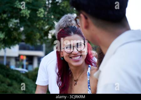 Young woman smiling and talking with friends outdoors in urban setting. Stock Photo