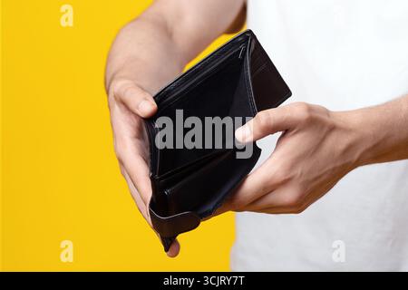 Unrecognizable man showing empty wallet at studio, closeup Stock Photo