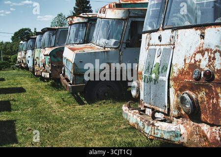 Row of Rusty Abandoned Trucks on Grass Field Stock Photo