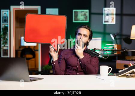 Influencer holding empty copy space sign in hand, showcasing message to audience without talking. Internet star using red cardboard bubble speech cutout to express opinions with no voice Stock Photo