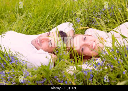 young couple lying head to head happily in a meadow Stock Photo