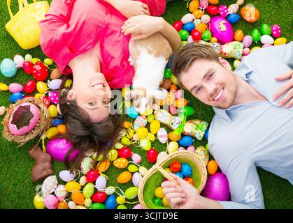 couple lying with an Easter bunny between many colourful Easter eggs on a meadow Stock Photo