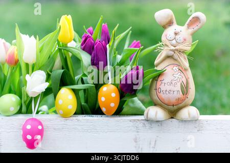 Tulips in a box with Easter eggs and an Easter bunny with the words Happy Easter on its belly Stock Photo