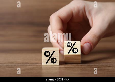Man holding wooden cube with percent sign at table, closeup Stock Photo