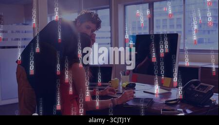 Collaborating woman in red blouse and coworker coding on office PC with binary overlay, copy space Stock Photo