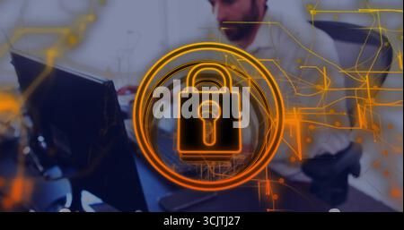 Displaying orange padlock icon over office worker with headphones at desk with circuit overlay Stock Photo