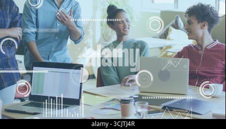 Collaborating colleagues analyzing data on laptops in office space, with smartphone and coffee mug Stock Photo
